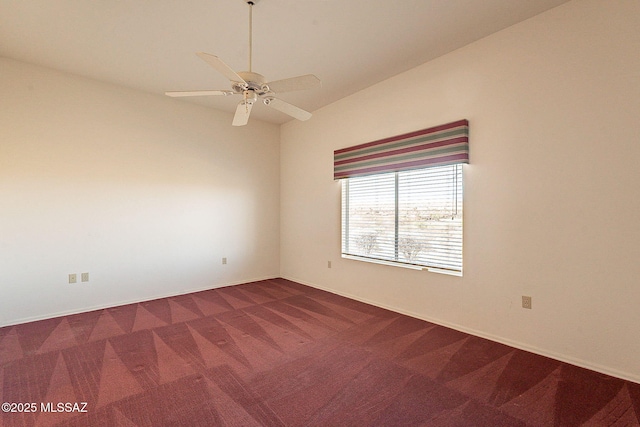 empty room featuring vaulted ceiling, dark carpet, and ceiling fan