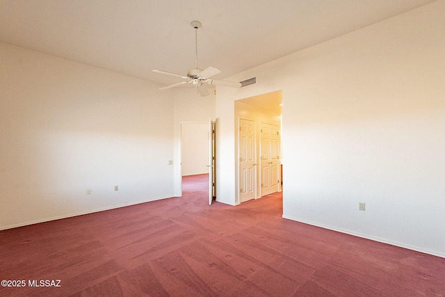 carpeted spare room with baseboards, visible vents, and a ceiling fan