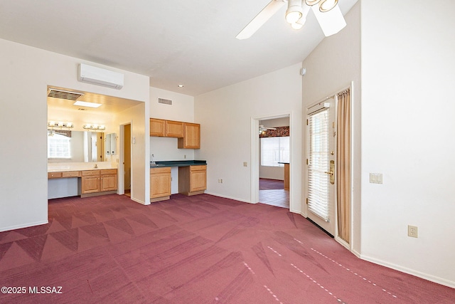 kitchen with a wall mounted air conditioner, dark carpet, visible vents, and baseboards