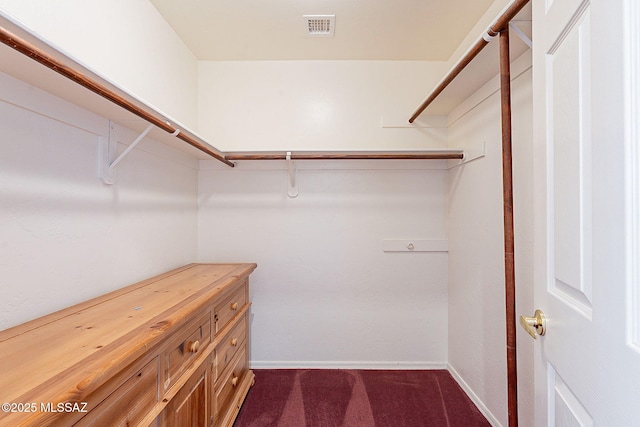 spacious closet with dark colored carpet and visible vents