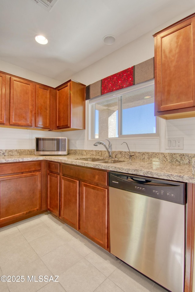 kitchen featuring brown cabinets, recessed lighting, appliances with stainless steel finishes, a sink, and light stone countertops