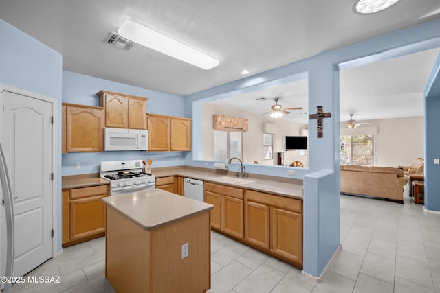 kitchen with a center island, light countertops, visible vents, a sink, and white appliances