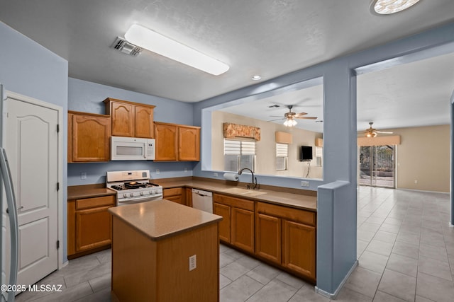 kitchen with white appliances, a kitchen island, a sink, visible vents, and a ceiling fan