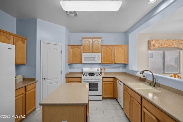 kitchen featuring white appliances, a sink, visible vents, light countertops, and a center island