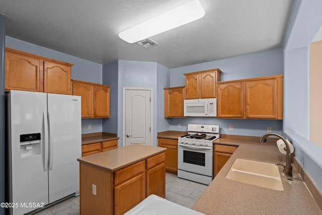 kitchen with a sink, a kitchen island, light tile patterned floors, white appliances, and visible vents