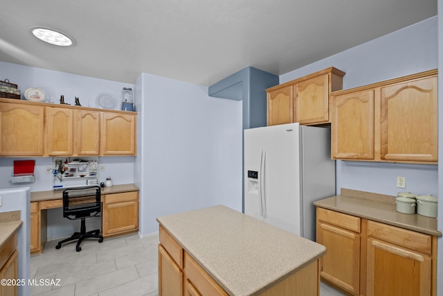 kitchen featuring a center island, built in desk, light countertops, light tile patterned flooring, and white fridge with ice dispenser