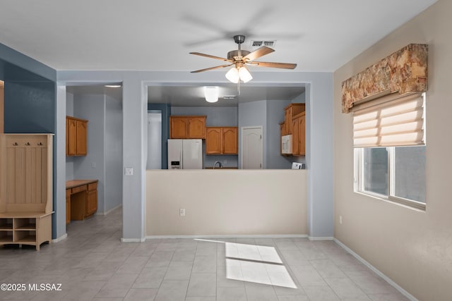 kitchen featuring visible vents, white appliances, baseboards, a ceiling fan, and brown cabinetry