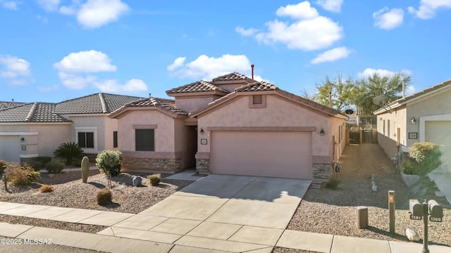 mediterranean / spanish home with stucco siding, a garage, stone siding, driveway, and a tiled roof