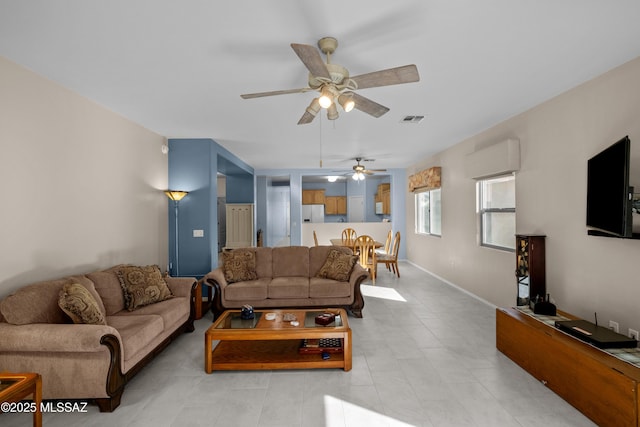 living room with ceiling fan, a wall unit AC, visible vents, and baseboards