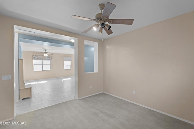 spare room with baseboards, ceiling fan, and carpet