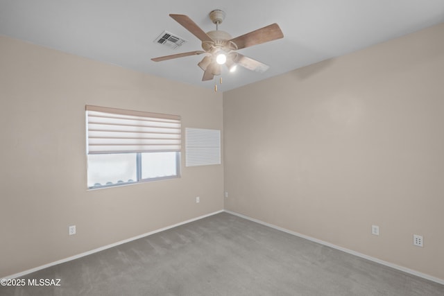 carpeted spare room with baseboards, ceiling fan, and visible vents