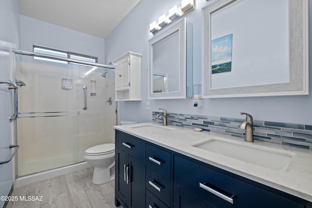 full bath with double vanity, a sink, toilet, and a shower stall