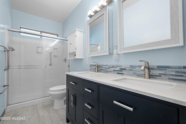 bathroom with toilet, a sink, a stall shower, and double vanity