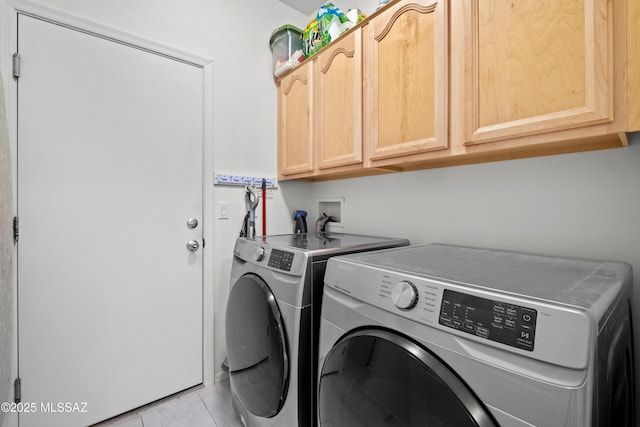 laundry area with cabinet space, light tile patterned floors, and separate washer and dryer