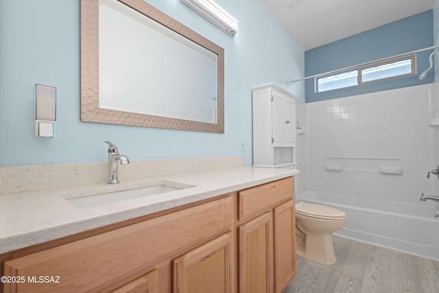 bathroom with wood finished floors, toilet, vanity, and shower / bathtub combination