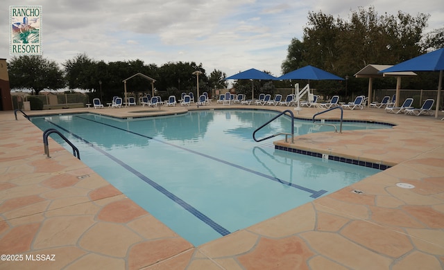 community pool with a patio area and fence