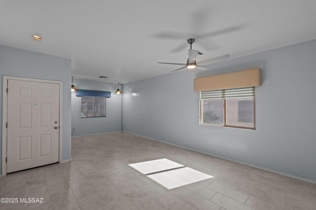 unfurnished room with a ceiling fan and baseboards