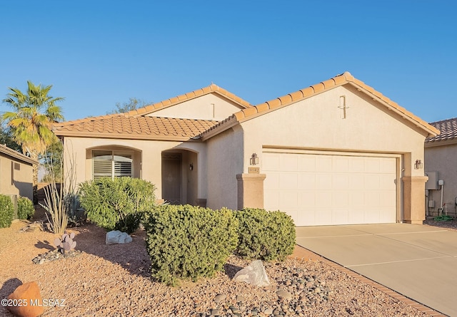 mediterranean / spanish-style home with a tiled roof, stucco siding, an attached garage, and driveway