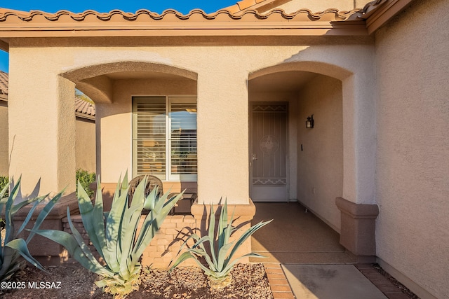 doorway to property featuring a tiled roof and stucco siding