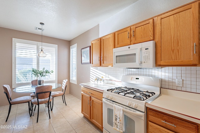 kitchen with visible vents, decorative light fixtures, white appliances, light countertops, and decorative backsplash