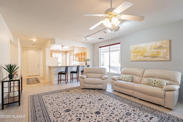 living area featuring light tile patterned floors, rail lighting, and ceiling fan