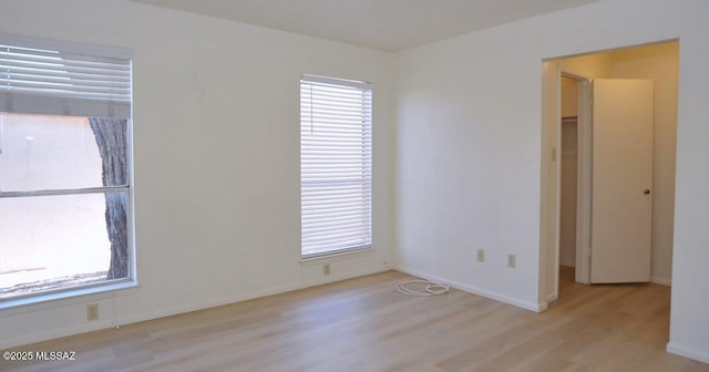 empty room with baseboards, wood finished floors, and a healthy amount of sunlight