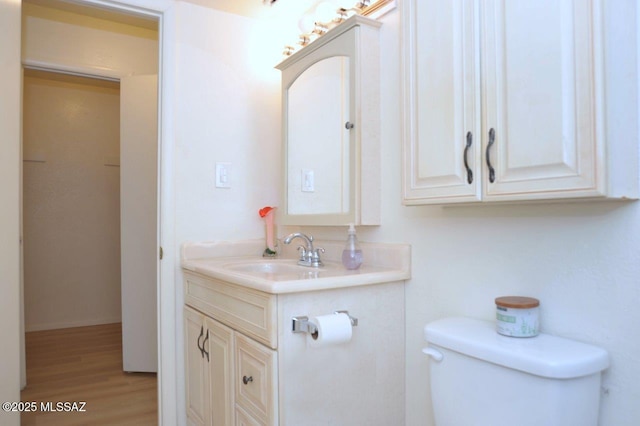 half bath with vanity, toilet, and wood finished floors