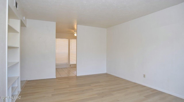 unfurnished room featuring a textured ceiling, wood finished floors, and visible vents