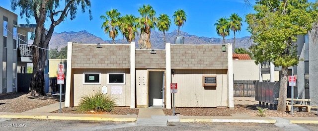 multi unit property featuring a shingled roof, a mountain view, and fence