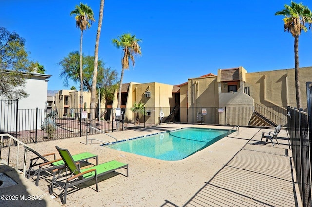 community pool featuring a patio area, a residential view, and fence