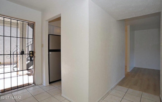 interior space featuring baseboards, a textured ceiling, and light tile patterned flooring