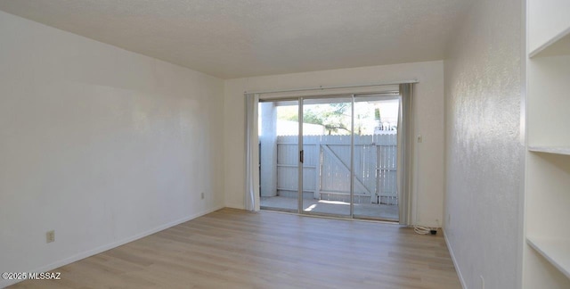 unfurnished room with light wood-type flooring, baseboards, a textured ceiling, and a textured wall