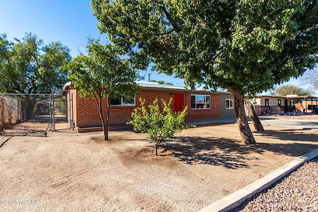 single story home with a carport, brick siding, fence, and a gate