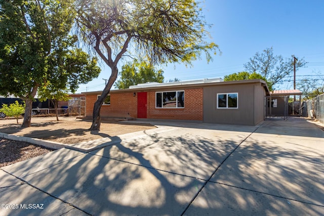 single story home featuring an attached carport, brick siding, fence, and driveway