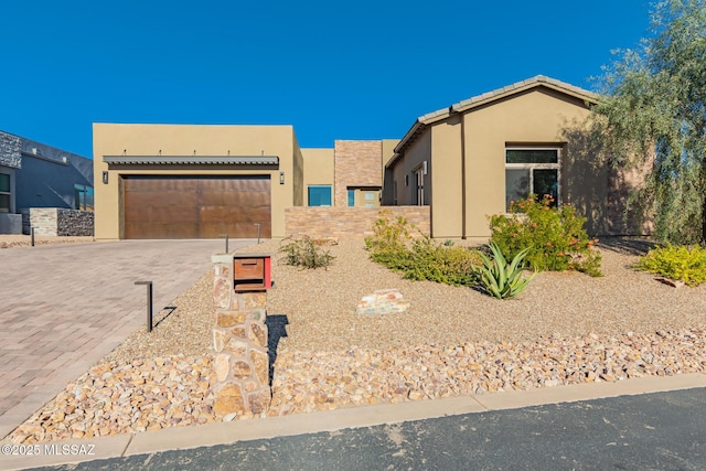 view of front of property with a garage, a tile roof, decorative driveway, and stucco siding