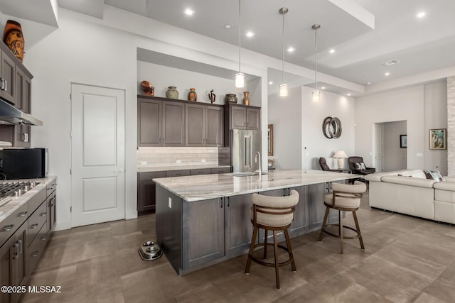 kitchen with stainless steel appliances, backsplash, a high ceiling, open floor plan, and light stone countertops