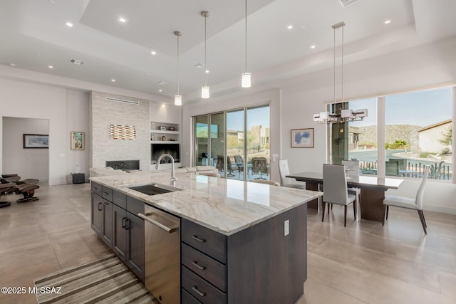 kitchen featuring built in shelves, a sink, open floor plan, stainless steel dishwasher, and a raised ceiling