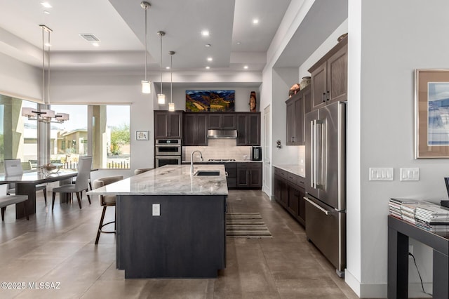 kitchen featuring visible vents, decorative backsplash, stainless steel appliances, under cabinet range hood, and a sink