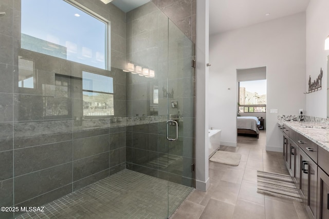 ensuite bathroom with baseboards, connected bathroom, tile patterned flooring, vanity, and a shower stall