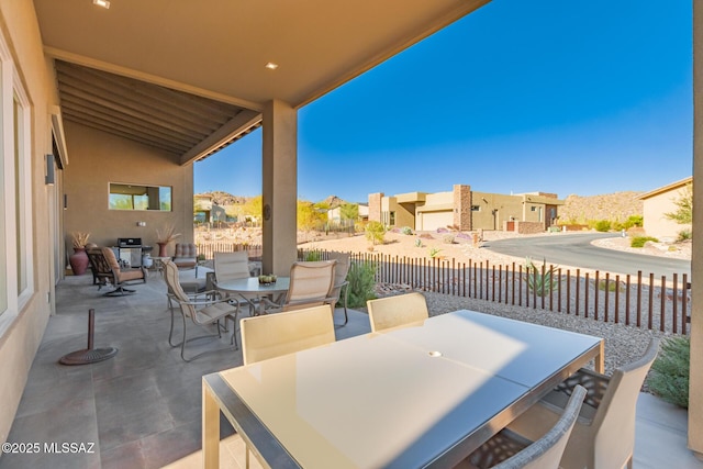 view of patio / terrace featuring outdoor dining area, fence, and a residential view