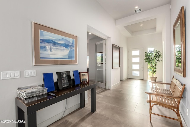 interior space with a tray ceiling, visible vents, and baseboards