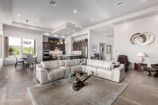 living area with recessed lighting, visible vents, a notable chandelier, and a towering ceiling