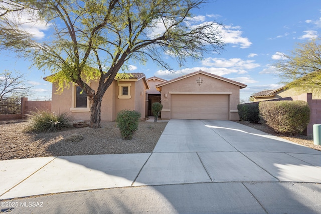 mediterranean / spanish home featuring a garage, concrete driveway, a tile roof, fence, and stucco siding