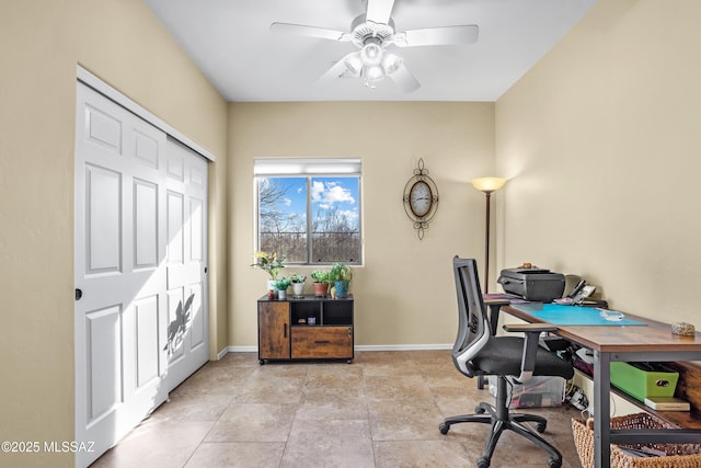 office space with a ceiling fan and baseboards