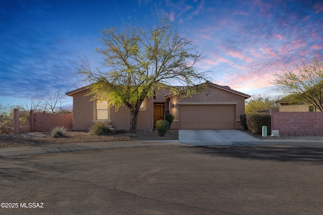 view of front of house with a garage, fence, driveway, and stucco siding