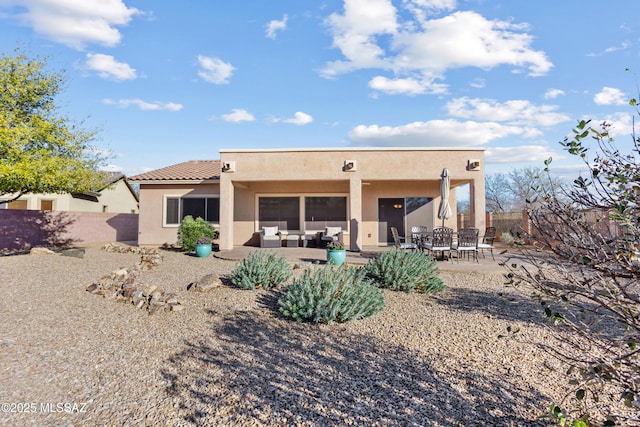 rear view of property with fence, outdoor lounge area, a patio, and stucco siding