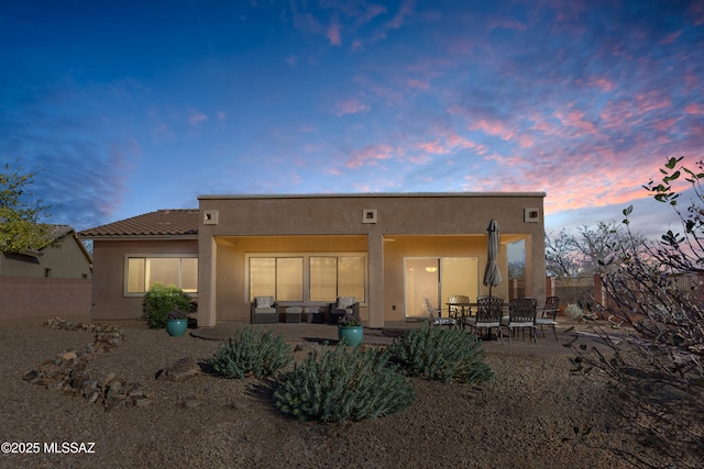 back of property with a tile roof, fence, a patio, and stucco siding