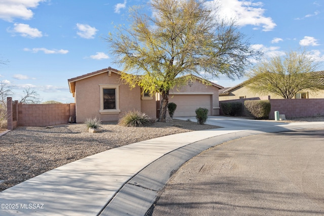 view of front facade with concrete driveway, a tile roof, an attached garage, fence, and stucco siding