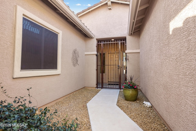 property entrance with a gate and stucco siding