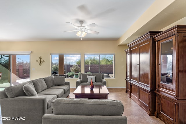 living area with a ceiling fan, baseboards, and light tile patterned floors